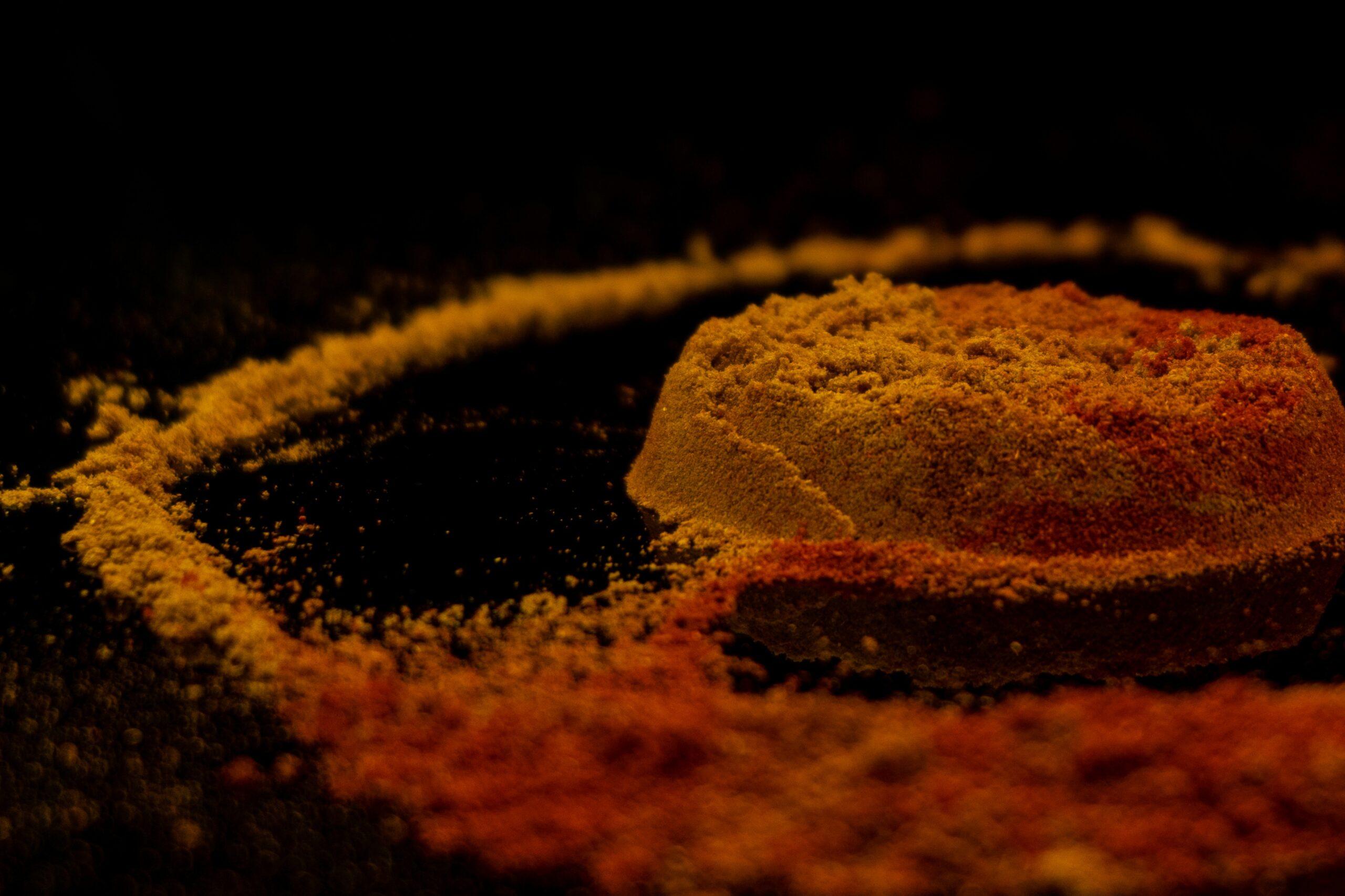 A bowl of vibrant yellow turmeric powder against a wooden background.