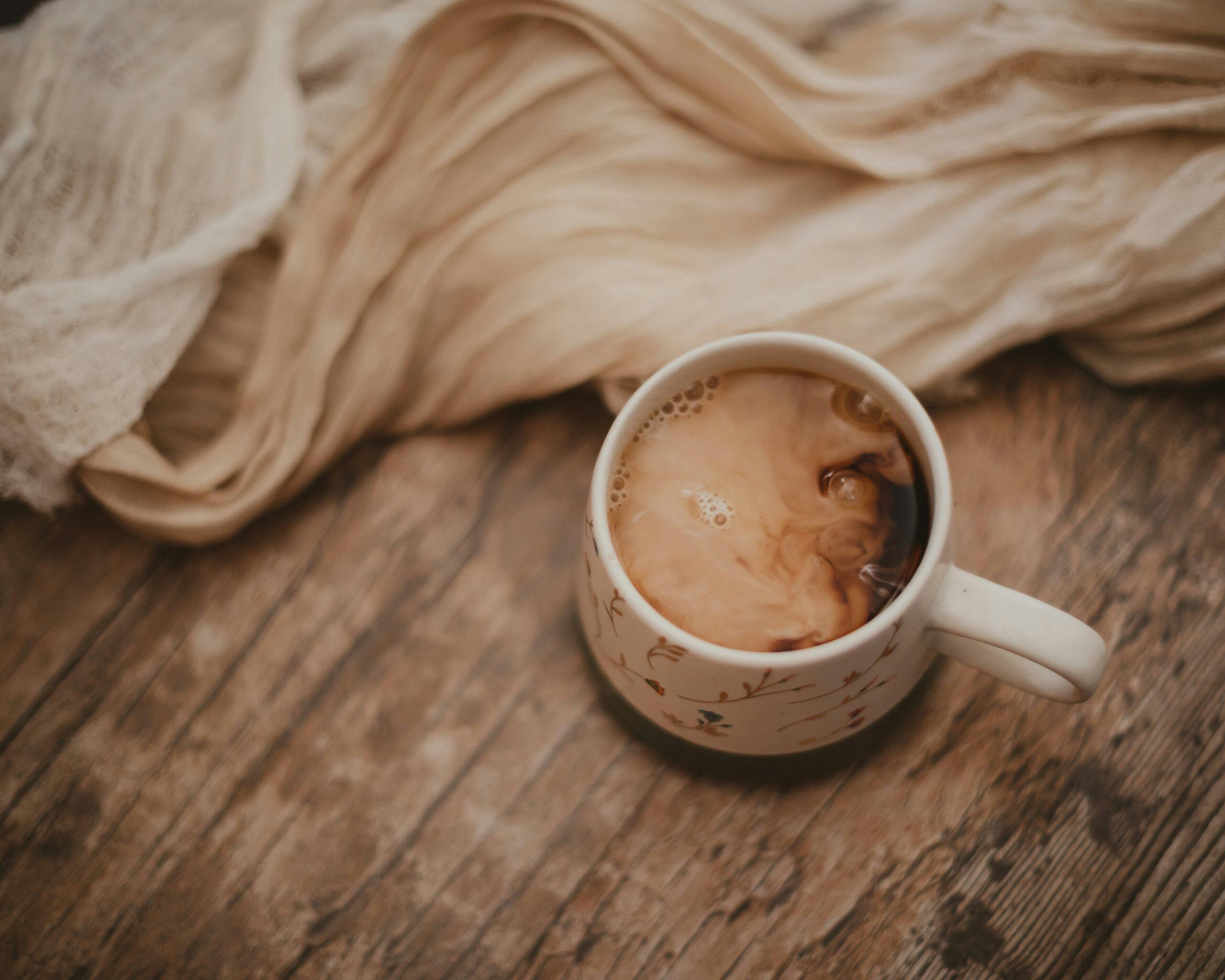 A cozy cup of golden milk topped with cinnamon and nutmeg against a rustic wooden table