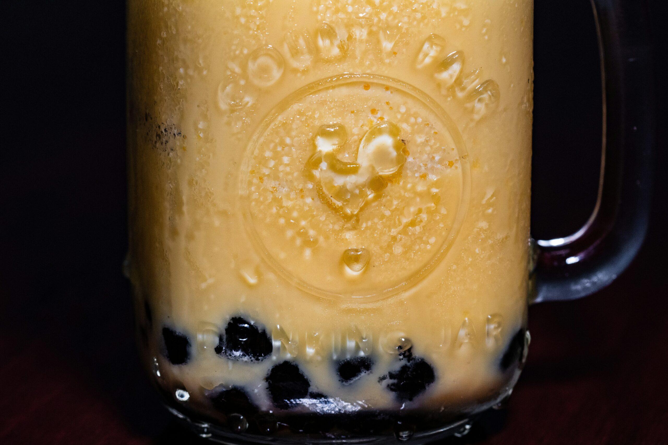 A glass mug filled with creamy golden milk topped with cinnamon sprinkles.