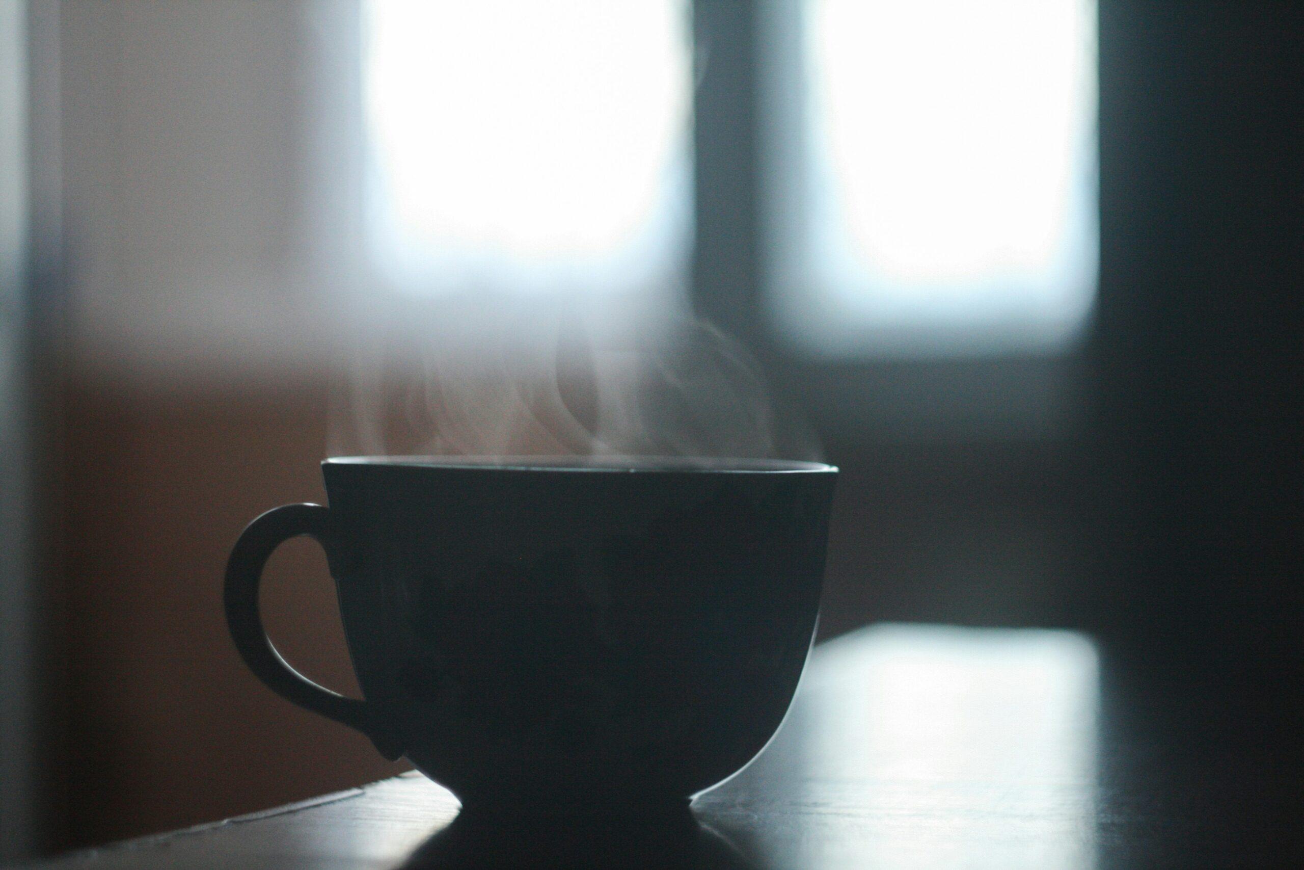 A person pouring hot water over turmeric powder in a mug to make tea