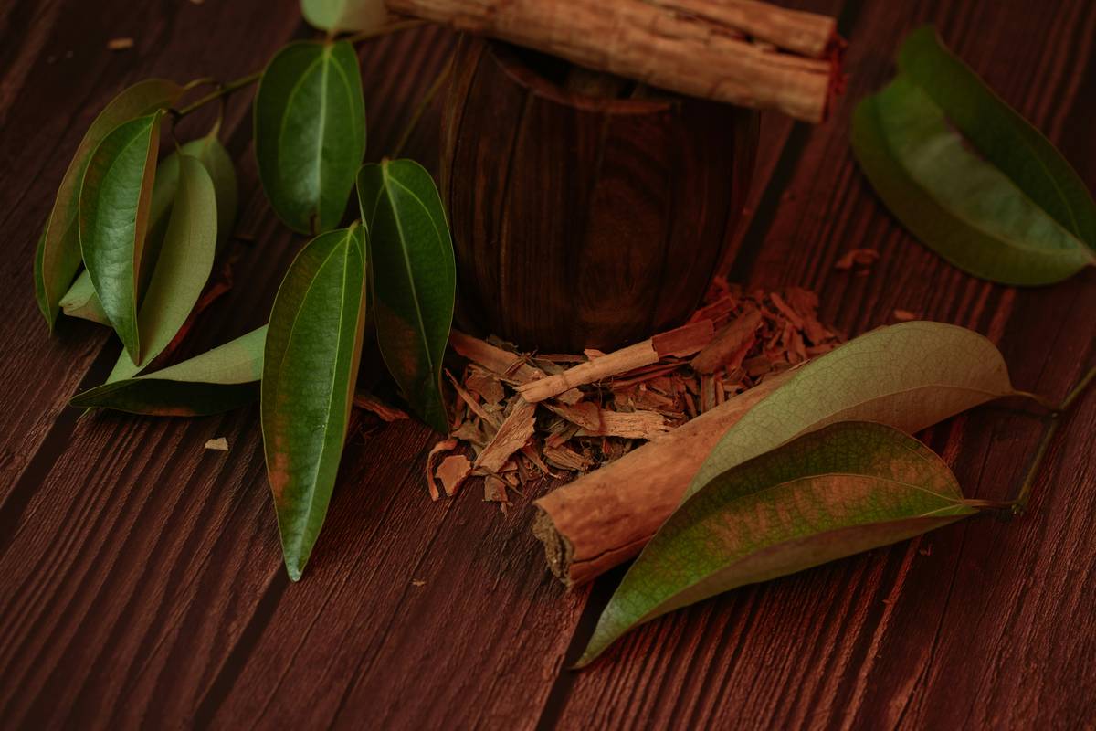 A jar of fresh turmeric root on a wooden counter next to peppercorns