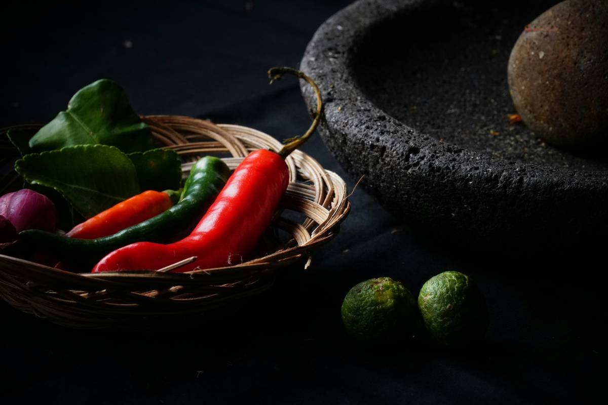 A bowl of fresh turmeric root next to a glass jar labeled 'turmeric powder'